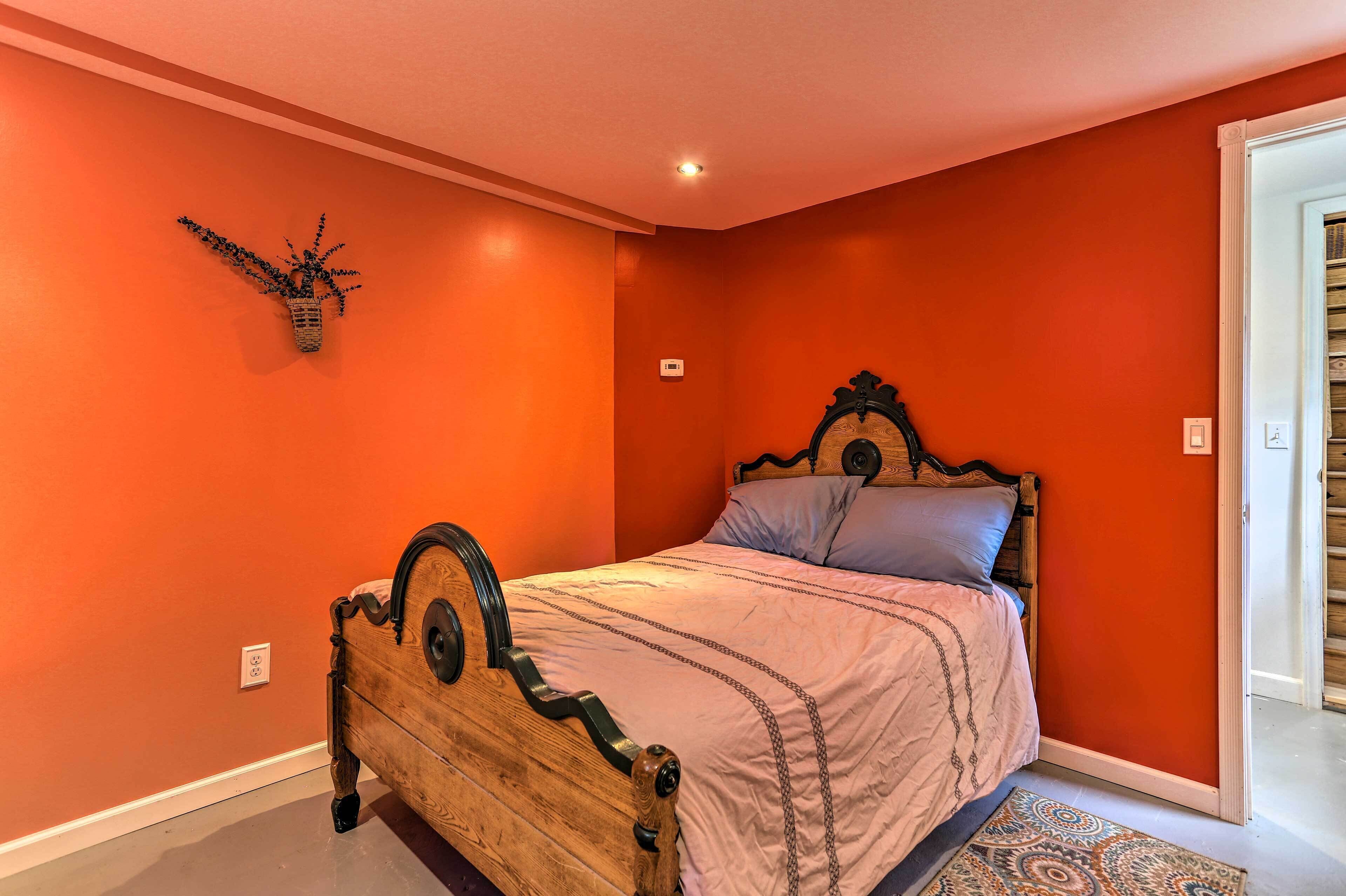 A bedroom with a wooden bed, orange walls, and a patterned rug.