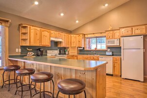A kitchen with wooden cabinets, a central island with stools, a microwave, a refrigerator, and a dishwasher.