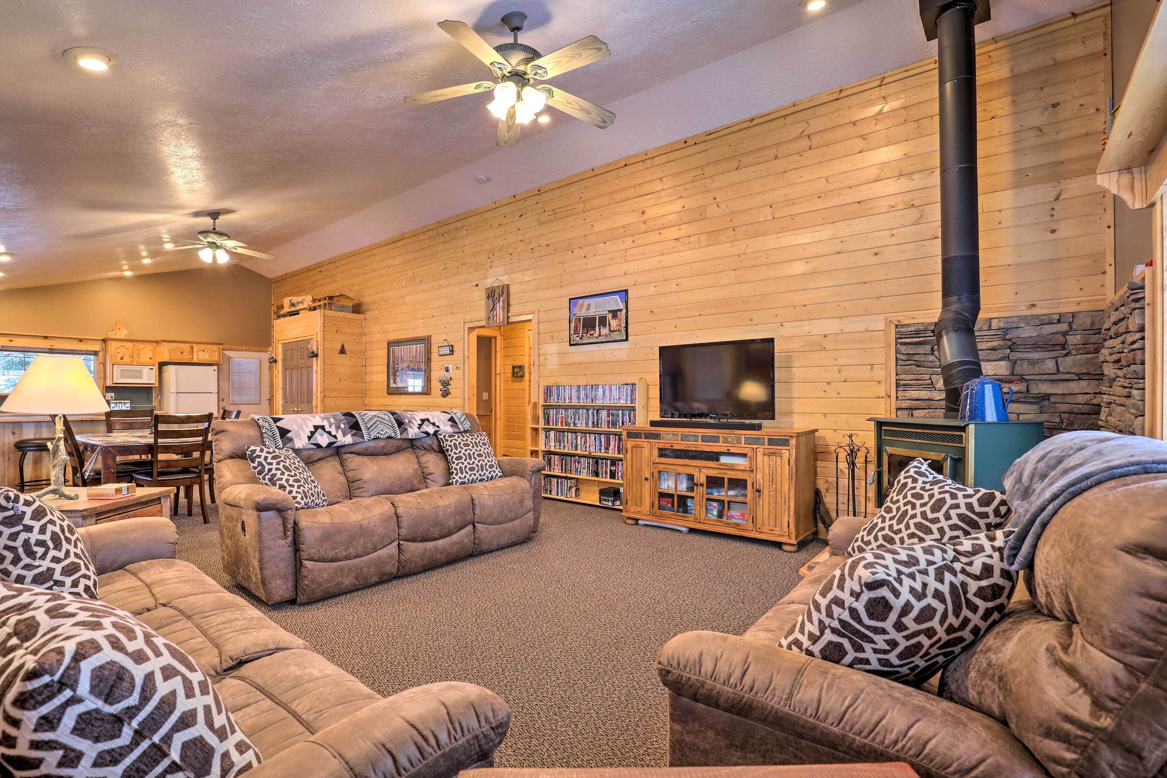 A cozy living room with a fireplace, wooden walls, a television, and a bookshelf.
