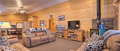 A cozy living room with a fireplace, wooden walls, a television, and a bookshelf.