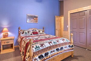A bedroom with a wooden bed, a nightstand with a lamp, a door, and a wall with a painting.