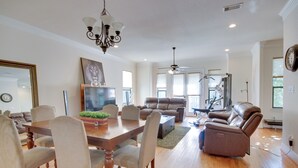 A spacious living room with a dining area, leather sofas, a massage chair, and a ceiling fan. - Pet-friendly Houston Home ~ 7 Mi to Downtown! (Houston)
