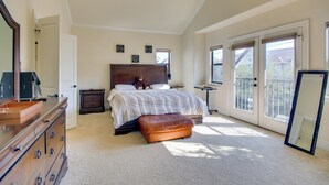 A spacious bedroom with a large bed, a dresser, a mirror, and a balcony with a view. - Pet-friendly Houston Home ~ 7 Mi to Downtown! (Houston)