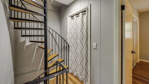 A staircase with wooden steps and black railings, leading to a room with a patterned shower curtain and a door with a handle. - 'bear Crossing Chalet:' Beech Mountain Family Home (Banner Elk)