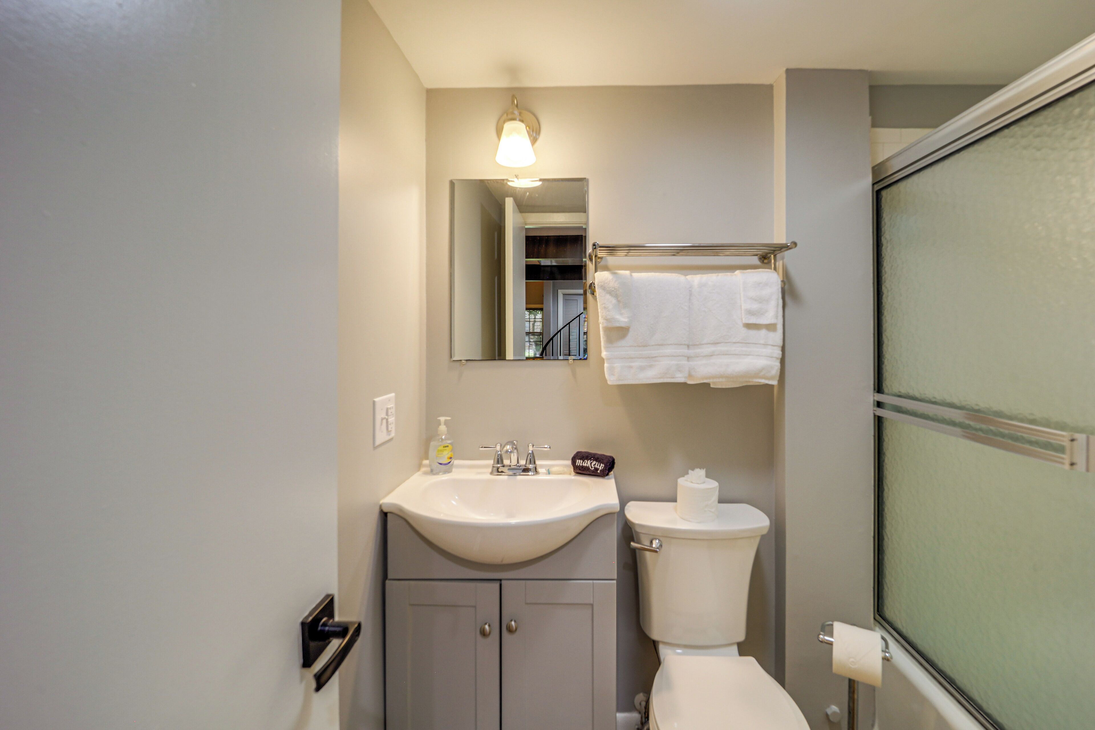 A bathroom with a sink, mirror, toilet, and towel rack.