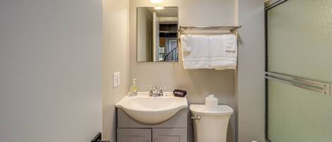 A bathroom with a sink, mirror, toilet, and towel rack.