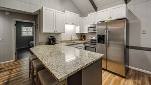 A modern kitchen with white cabinets, a granite countertop, stainless steel appliances, and a wooden floor. - 'bear Crossing Chalet:' Beech Mountain Family Home (Banner Elk)