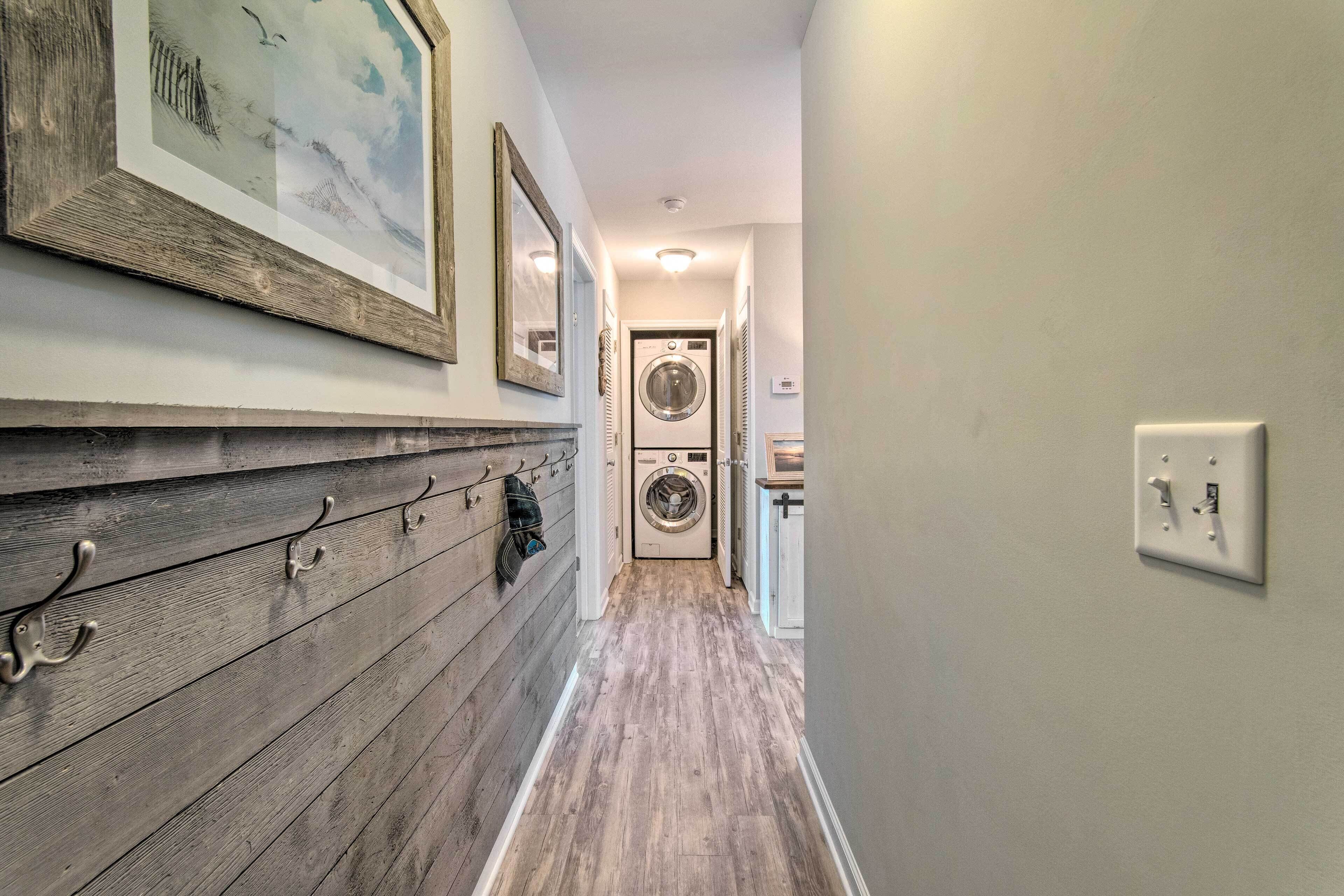 A laundry room with a washer and dryer, wooden wall paneling, and a framed picture.