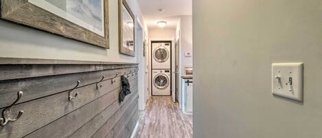 A laundry room with a washer and dryer, wooden wall paneling, and a framed picture.
