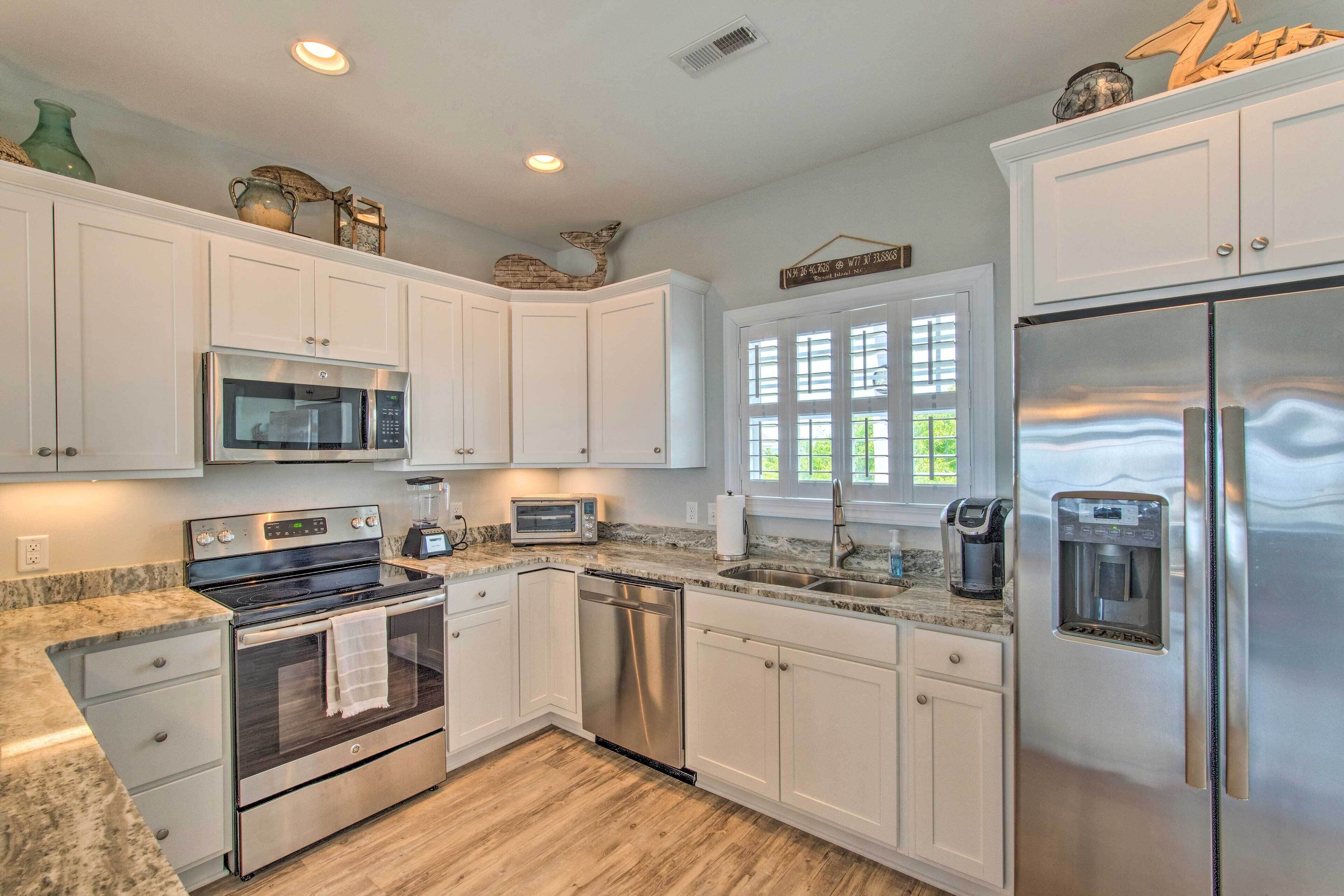 A modern kitchen with white cabinets, stainless steel appliances, and a granite countertop.