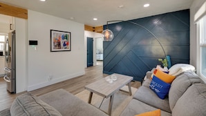 Un salon moderne avec un canapé gris, une table basse en bois et un mur d’accent bleu.
