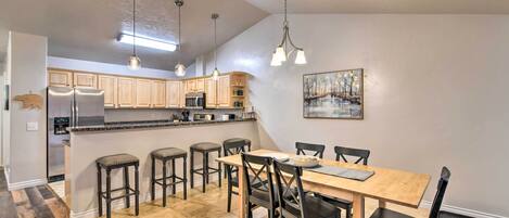 Una cocina moderna con armarios de madera, una isla central con taburetes e iluminación colgante.
