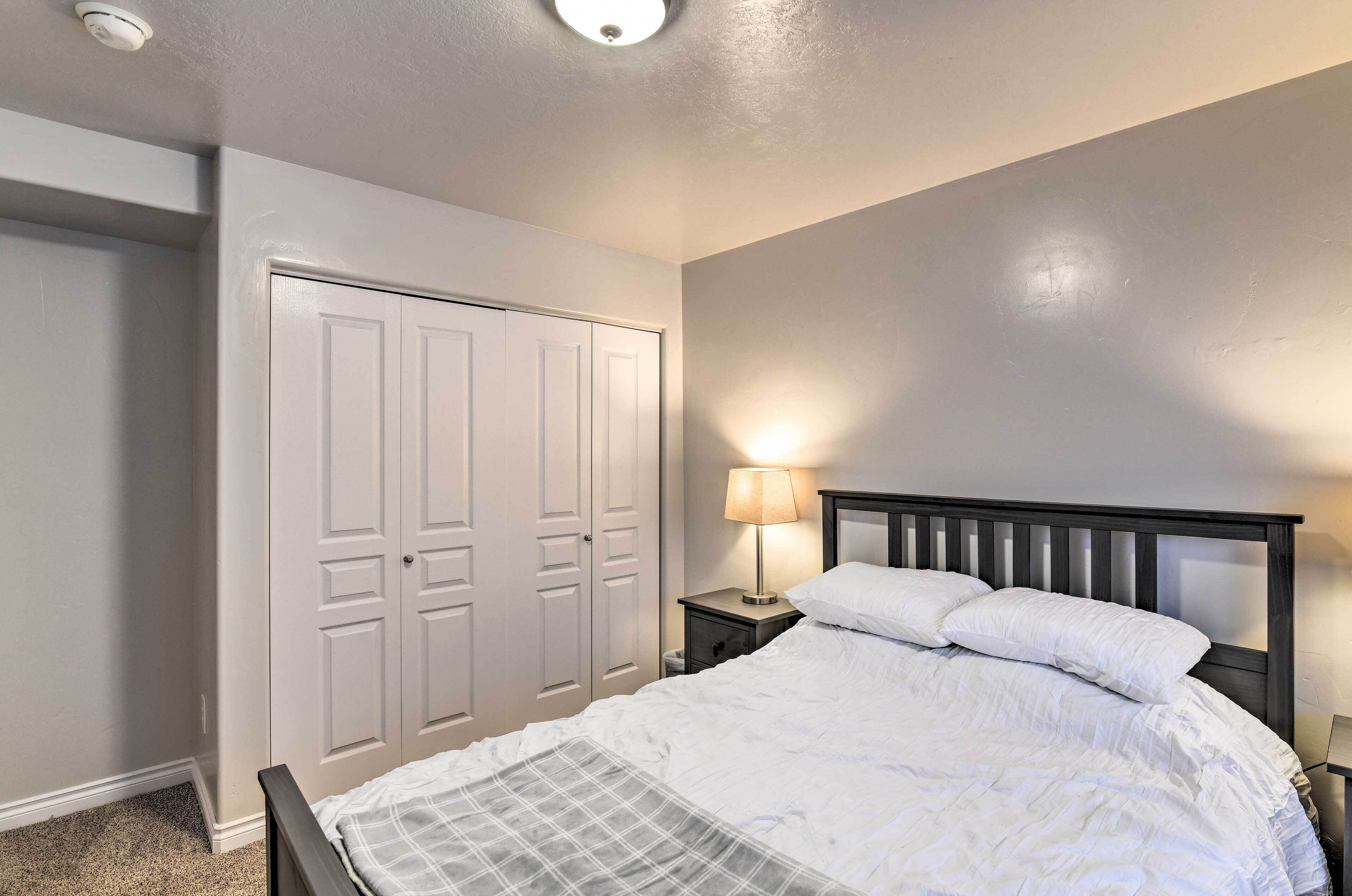 Een slaapkamer met een bed, een nachtkastje met lamp en een kledingkast.