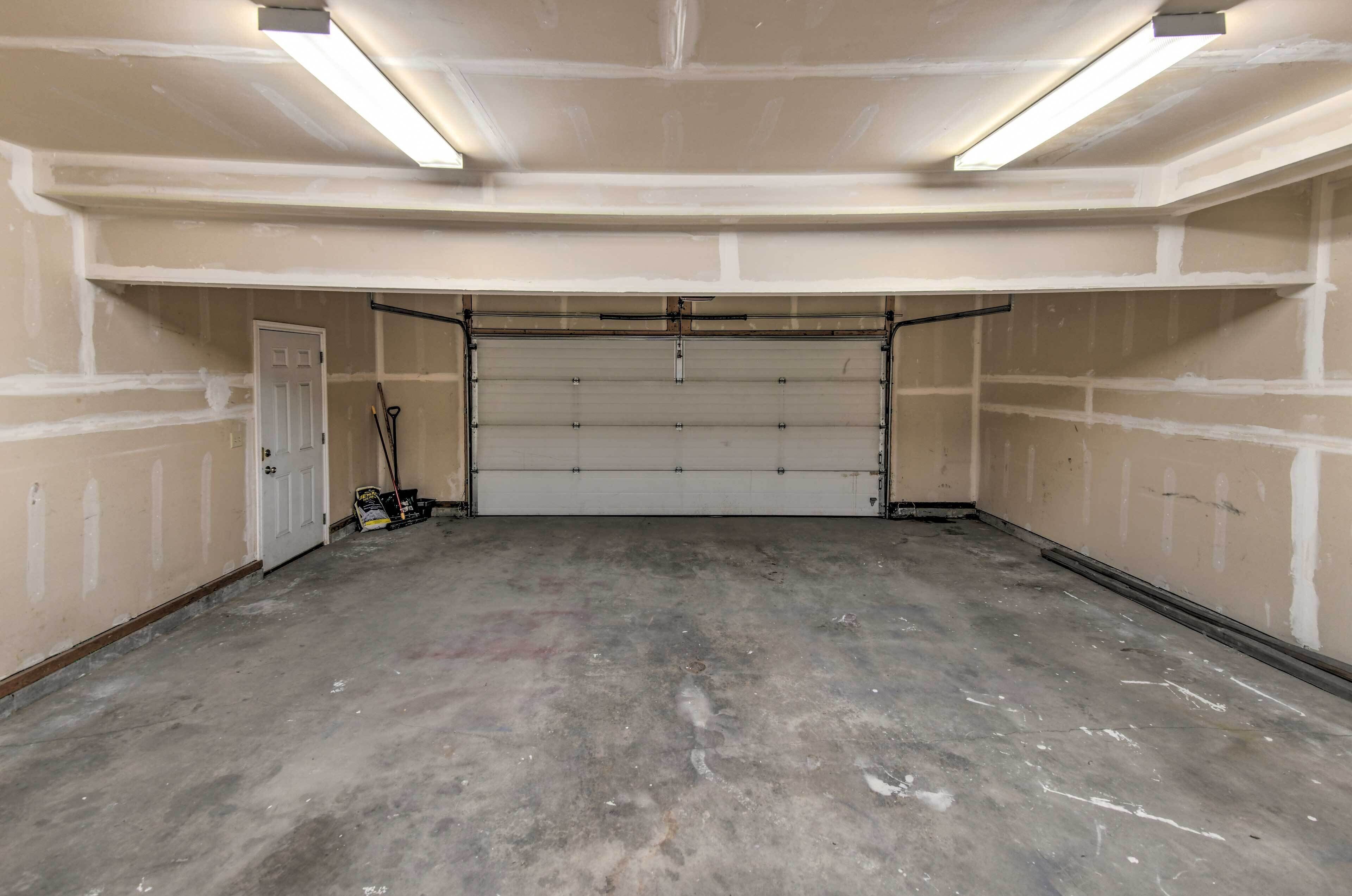 A garage with a closed garage door, fluorescent lighting, and a concrete floor.