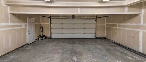A garage with a closed garage door, fluorescent lighting, and a concrete floor.