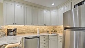 A kitchen with white cabinets, a stainless steel refrigerator, a dishwasher, and a coffee maker. - Brigantine Beach Retreat: Swim, Fish, & Shop! (Brigantine)