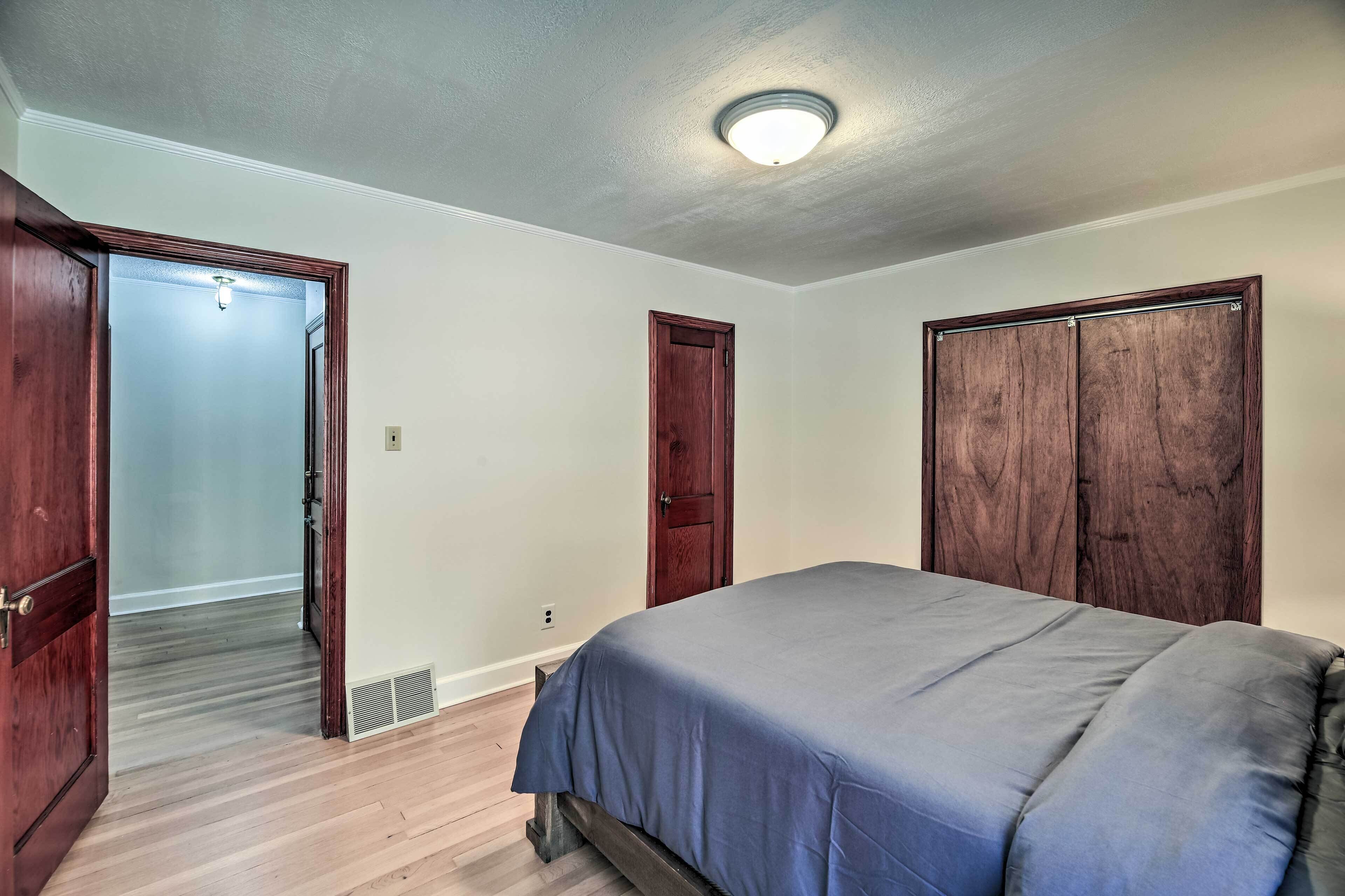 A bedroom with a bed, wooden wardrobe, and a door leading to another room.
