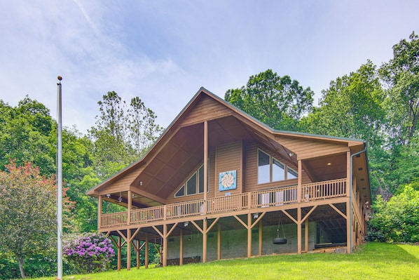 A wooden cabin with a balcony, large windows, and a porch.