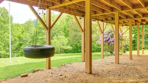 A covered outdoor area with a swing set, wooden beams, and a dirt ground. - Pisgah National Forest On-site: Home in Burnsville (Burnsville)