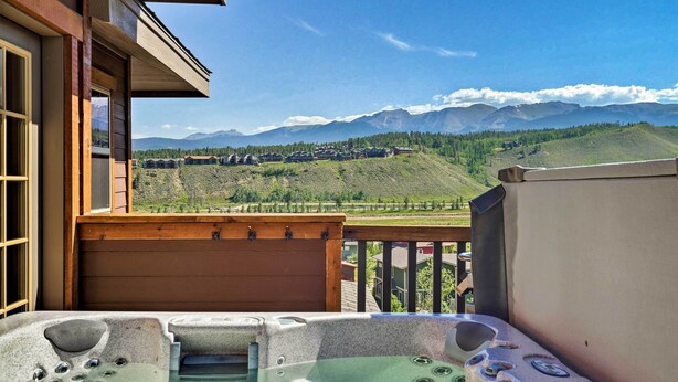 A balcony with a hot tub, wooden railings, and a view of a mountainous landscape. - Winter Park Retreat: Mtn Views & Pool Access! (Fraser)