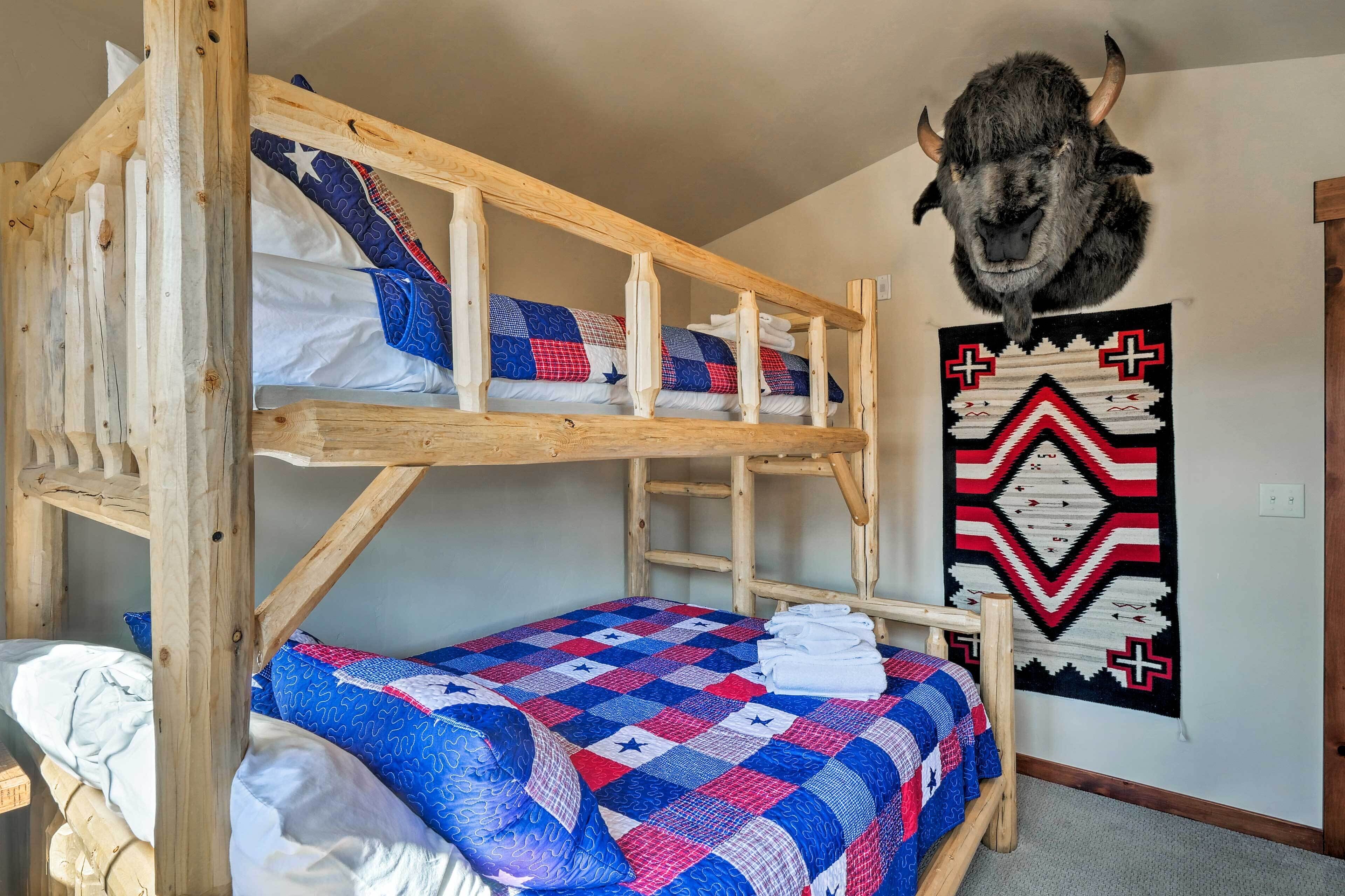A bunk bed with a quilted bedspread, a mounted buffalo head, and a Native American patterned wall hanging.