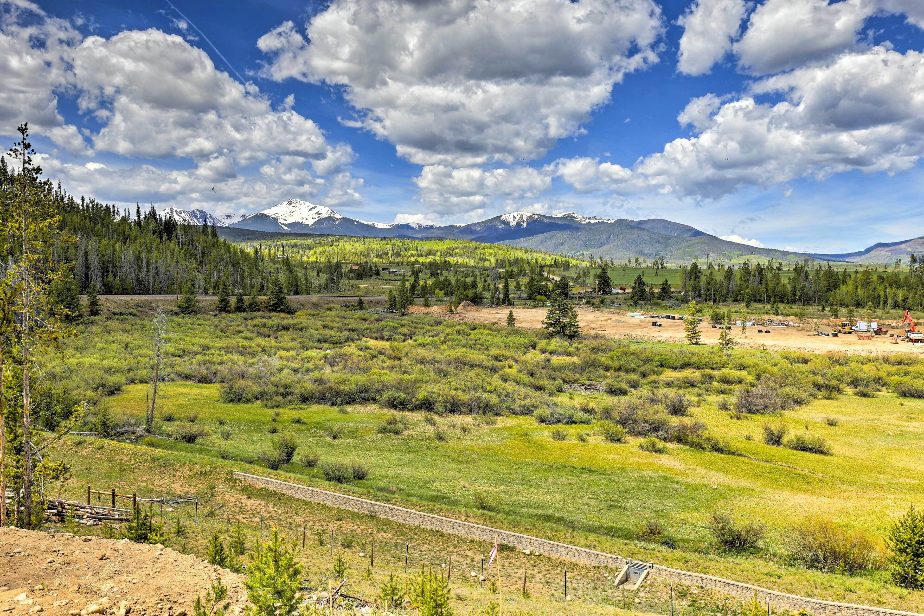 A mountainous landscape with a clear sky, a dirt road, and sparse vegetation.