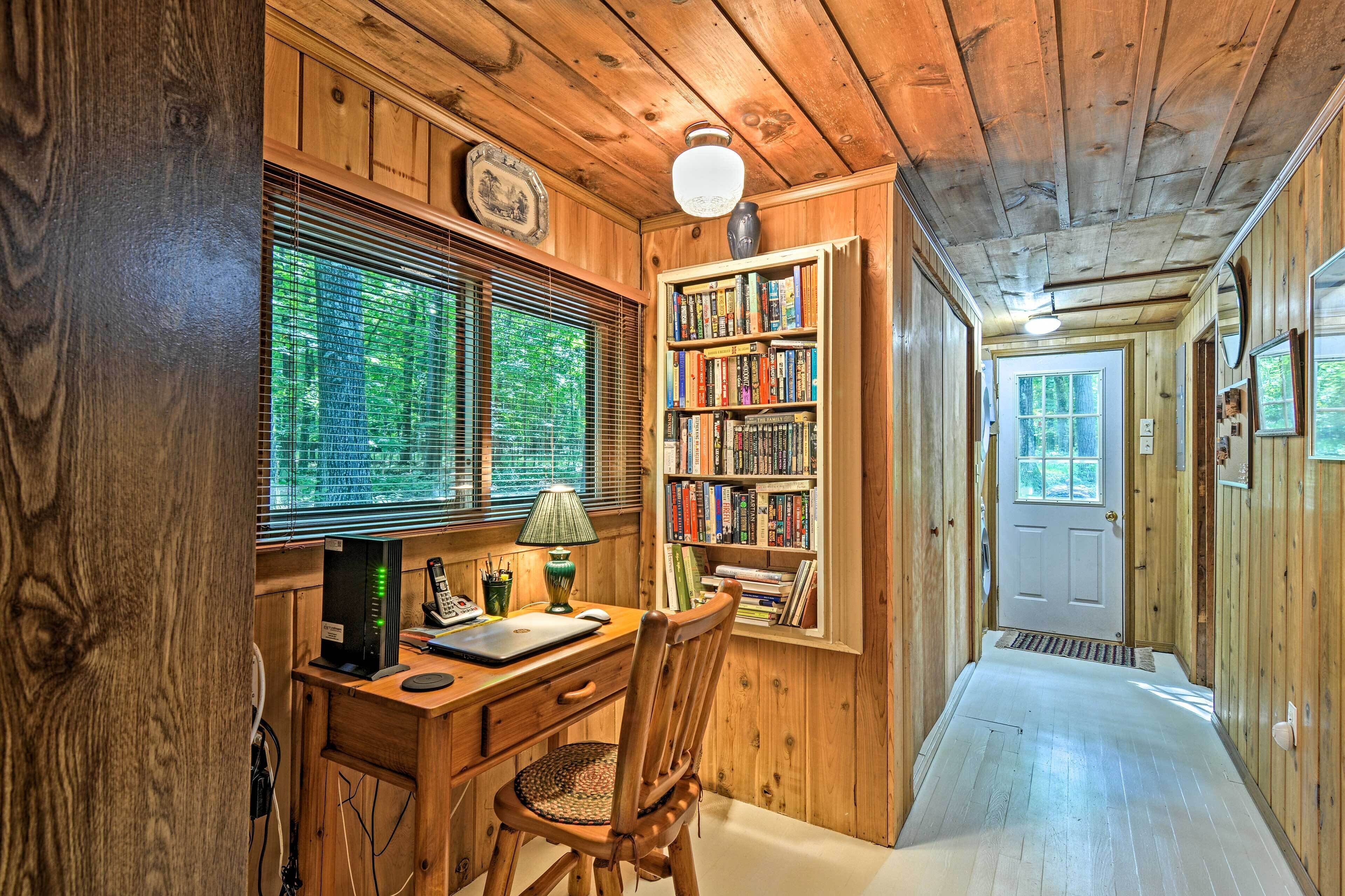 A wooden interior with a desk, chair, bookshelf, and a door leading to another room.