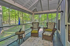 A covered porch with wicker furniture, a small table, and a bird on a stand. - Pet-friendly 'one Crow Cottage' in Harbor Springs! (Harbor Springs)