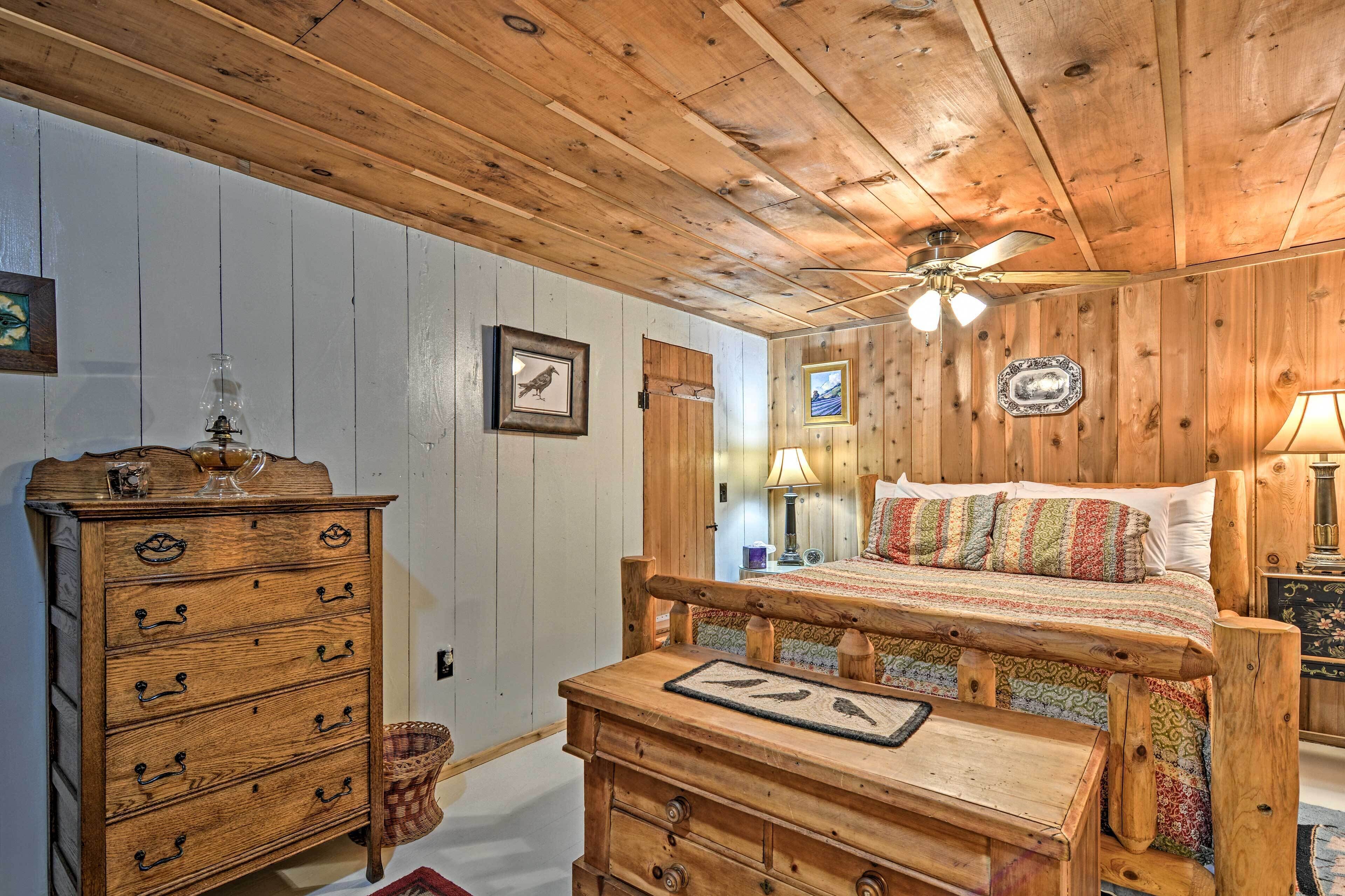 A wooden-paneled room with a bed, dresser, and a ceiling fan.