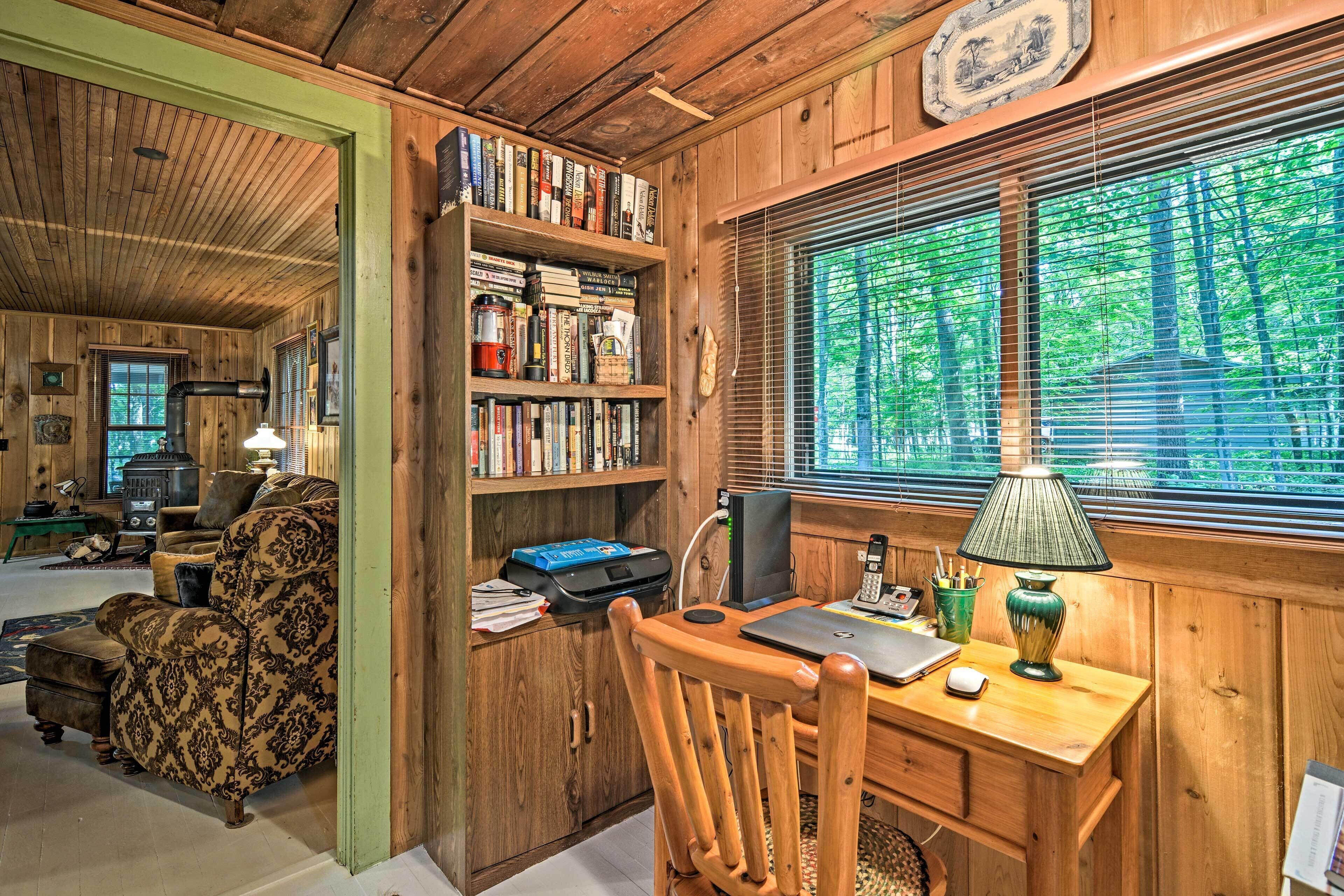 A cozy cabin interior with a wooden desk, bookshelves, and a fireplace.
