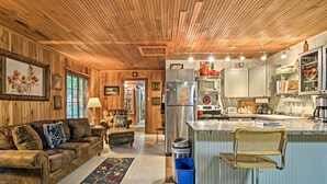Een knus interieur met houten lambrisering, een zithoek, keuken en een bar.