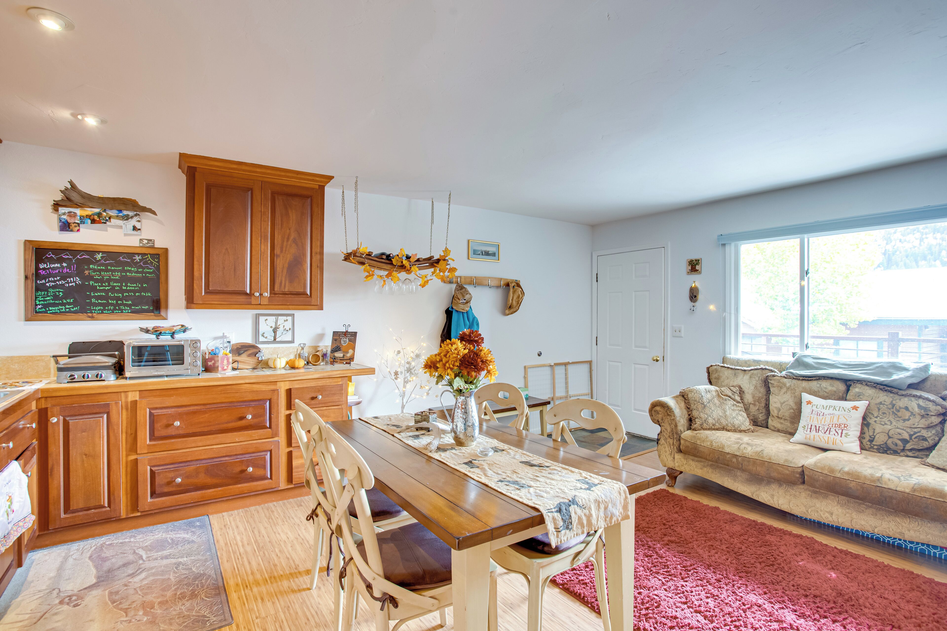 A cozy kitchen with wooden cabinets, a dining table, and a living area with a couch.