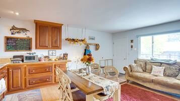 A cozy kitchen with wooden cabinets, a dining table, and a living area with a couch.