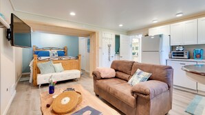 Un salon confortable avec un canapé, une table basse en bois et un téléviseur fixé au mur.