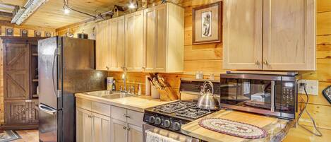 A wooden kitchen with a refrigerator, stove, microwave, and wooden cabinets.