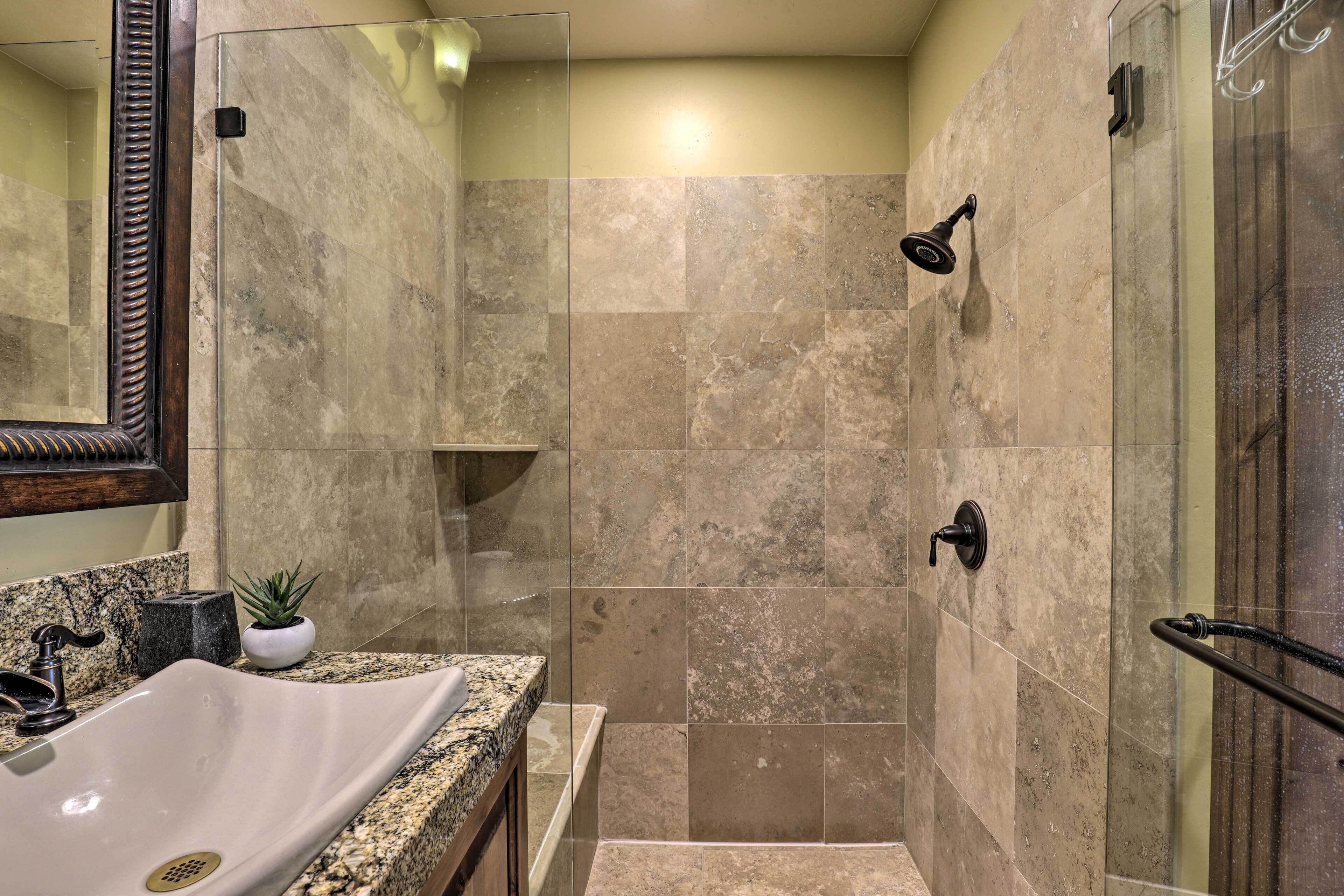 Une salle de bain avec un lavabo, un miroir, une douche et une petite plante posée sur le comptoir.