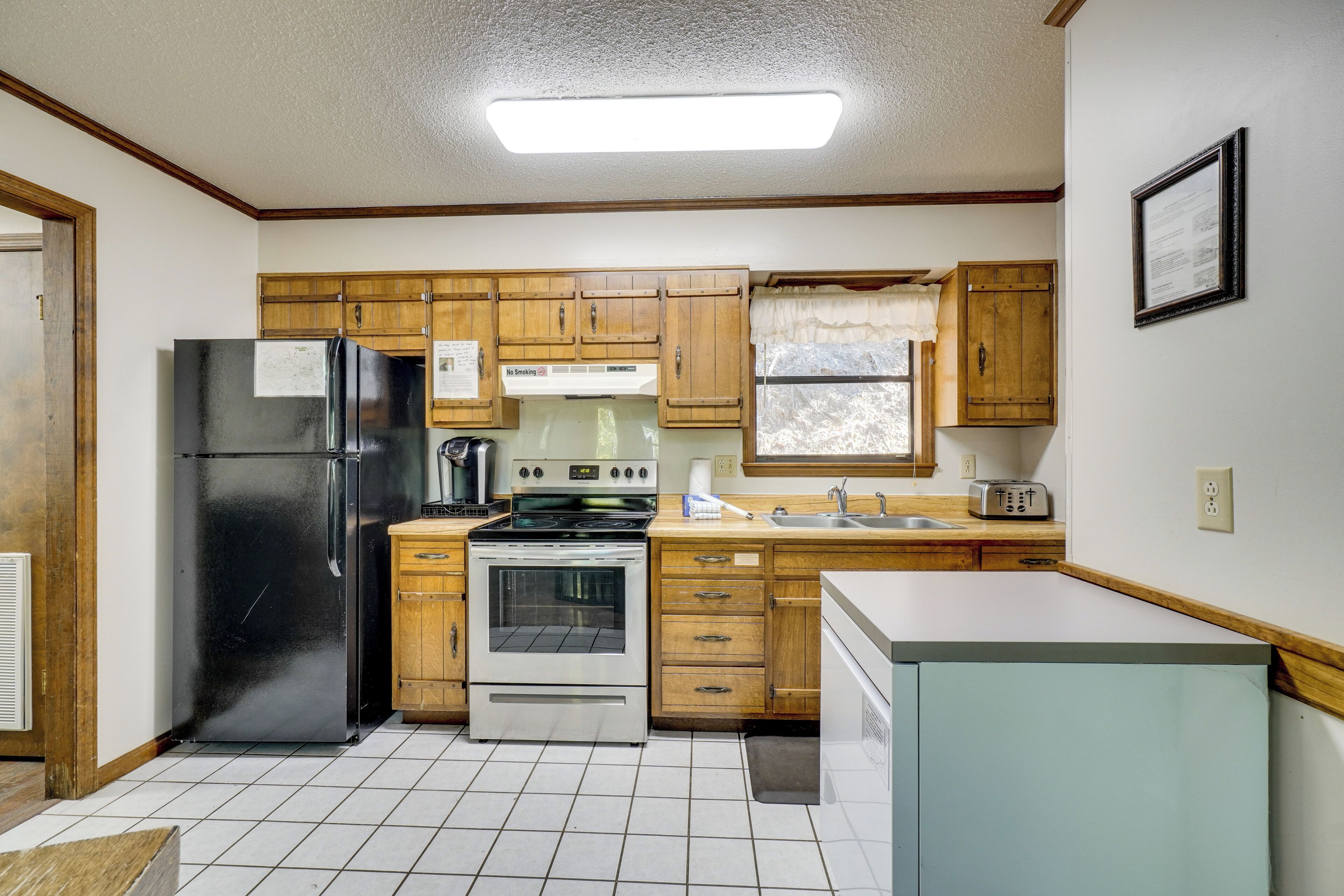 A compact kitchen with wooden cabinets, a black refrigerator, a stove, and a sink.