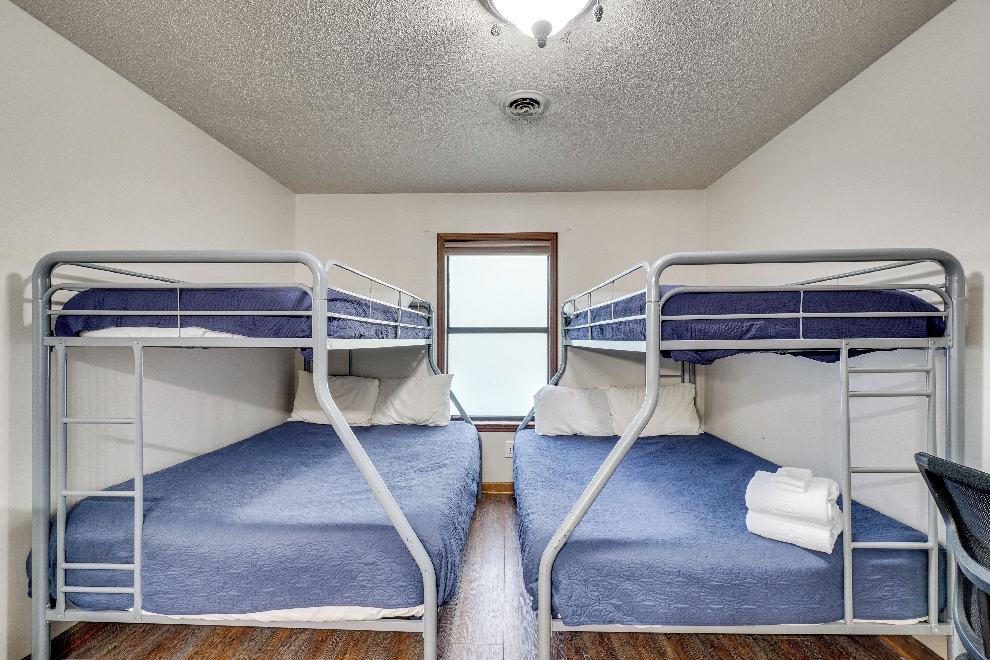 A room with two bunk beds, a window, and a door.