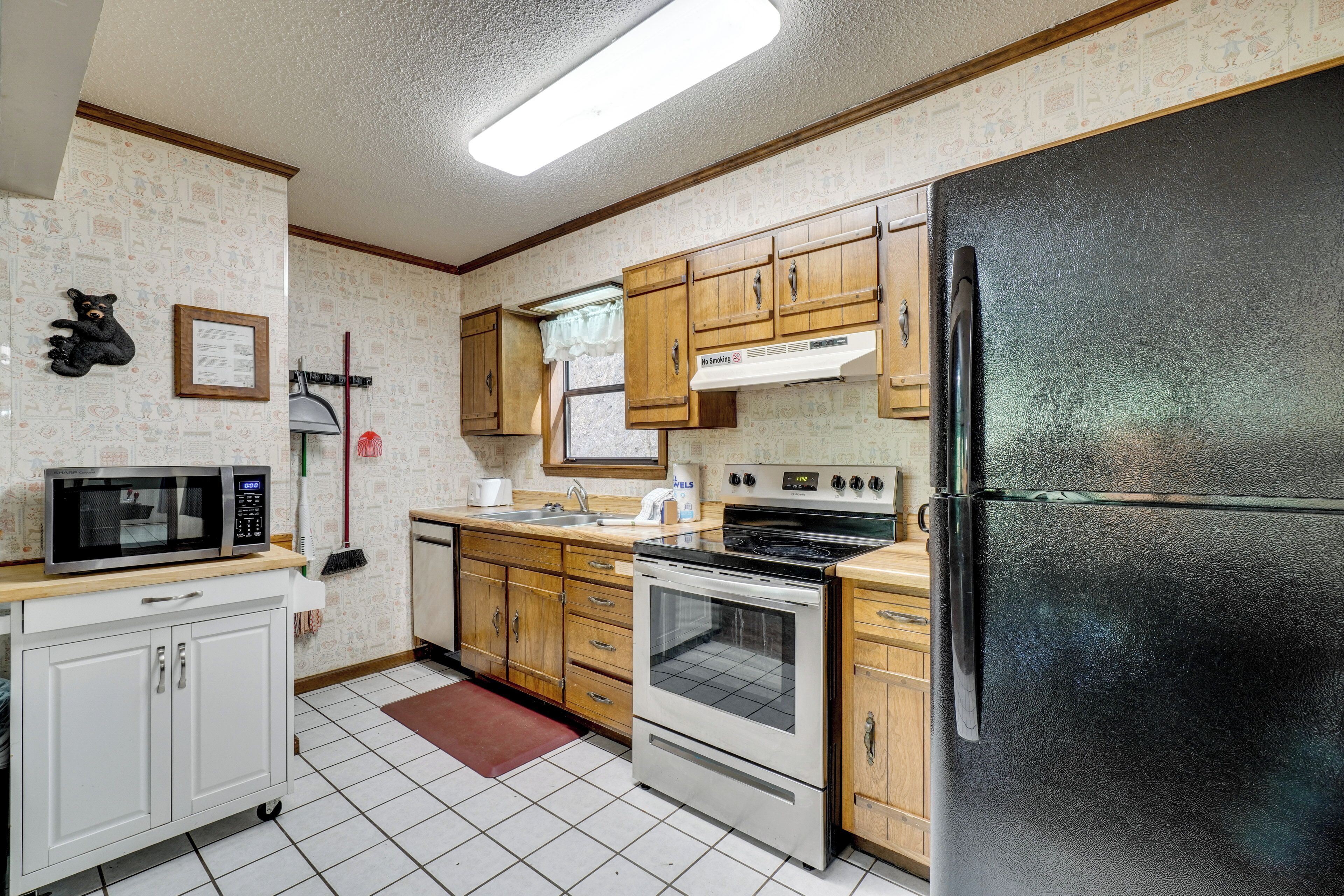 A kitchen with wooden cabinets, a black refrigerator, a stove, and a microwave.