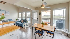 Un vaste espace de vie comprenant une table à manger en bois, un canapé bleu et un ventilateur de plafond.