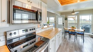 Une cuisine moderne dotée d’appareils électroménagers en acier inoxydable, de plans de travail en bois et d’un coin repas offrant une vue agréable.