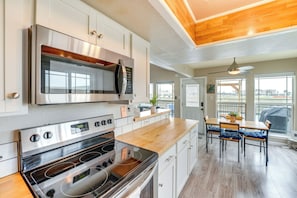 A modern kitchen with stainless steel appliances, wooden countertops, and a dining area with a view.