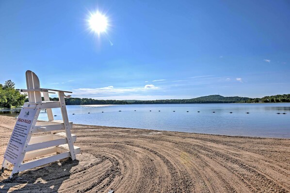 A beach with a signboard titled "BEACH RULES" and a wooden chair.