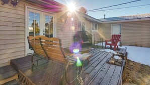 A wooden deck with a bench and chairs, a small table, and a house with a garage door. - Quaint Leadville Home w/ Grill: Walk to Dtwn! (Leadville)