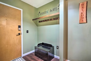 A hallway with a wooden door, a welcome sign, a coat rack, and a black storage bench. - Cozy Ski-in/ski-out Condo on Magic Mountain (Londonderry)