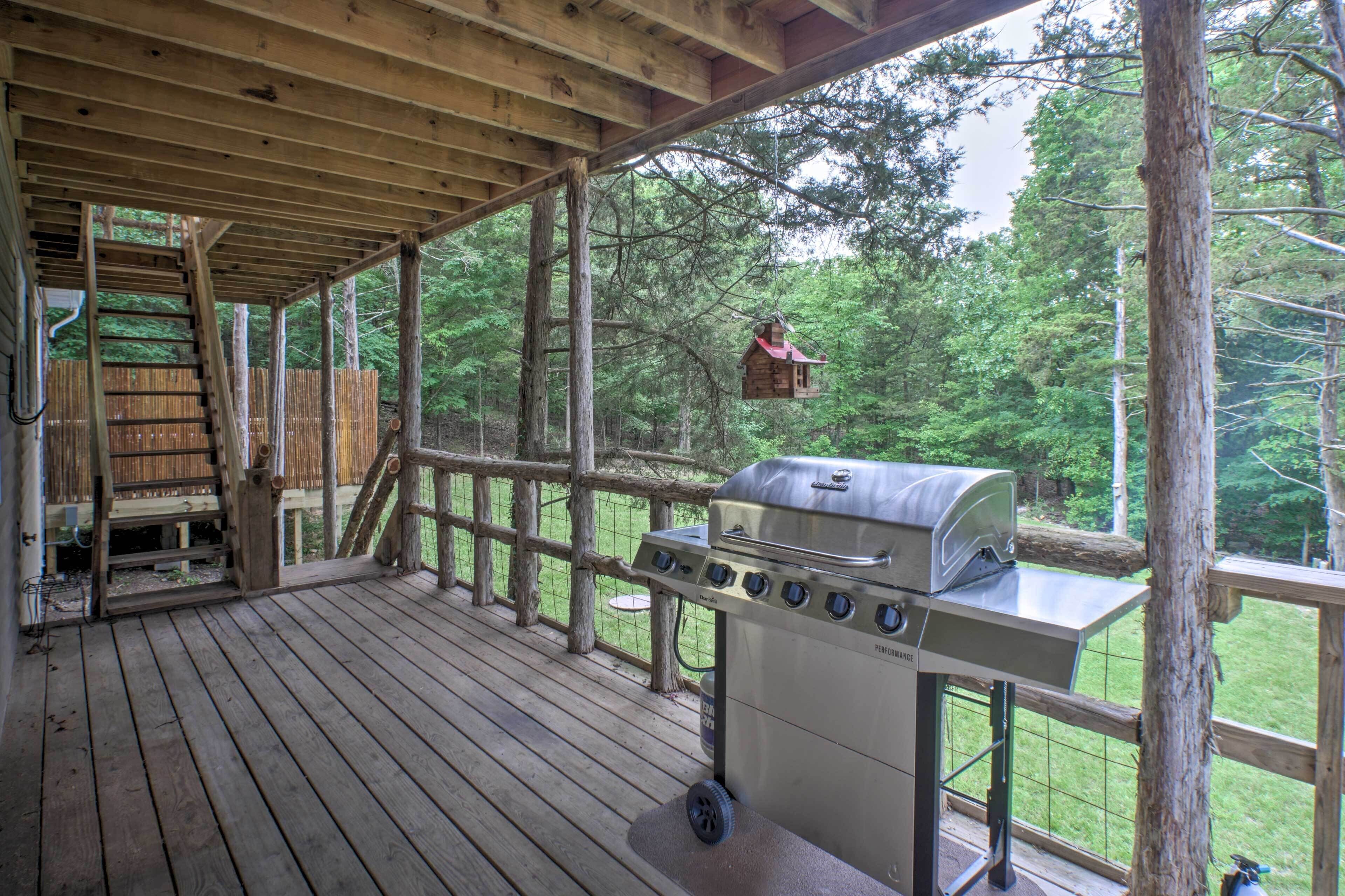 A covered wooden deck with a barbecue grill and a birdhouse.