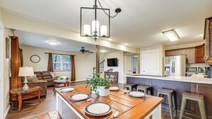 Une cuisine spacieuse avec une table à manger en bois pour quatre personnes, un îlot central intégré et un réfrigérateur moderne.