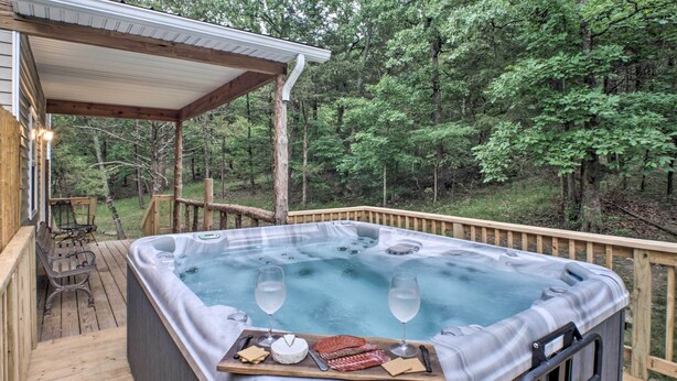 Un bain à remous avec une terrasse en bois, entouré d’arbres.