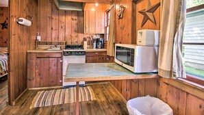 A rustic cabin kitchen with wooden walls, a stove, a microwave, and a star decoration. - Lake Retreat w/ Dock, Deck & Bbq, BYO Boat! (Dent)