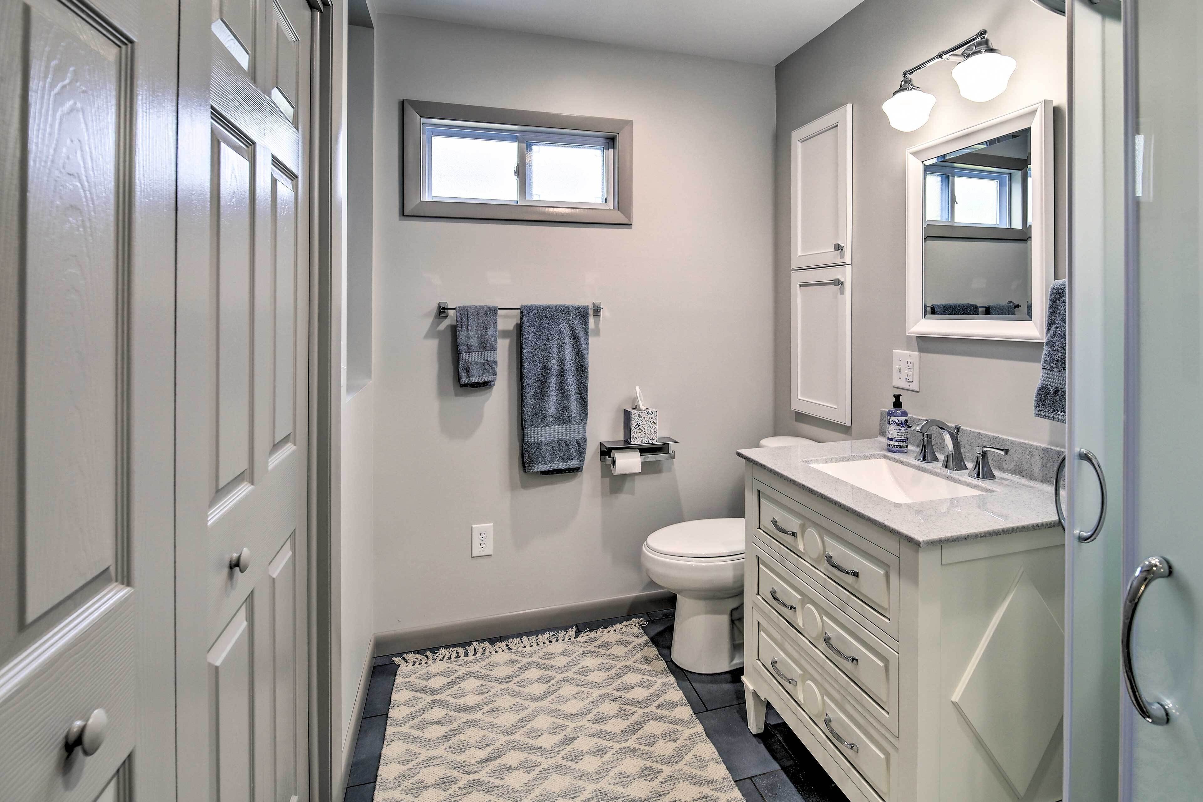 Une salle de bain comprenant des toilettes, un lavabo, un meuble-lavabo et une fenêtre située au-dessus des toilettes.